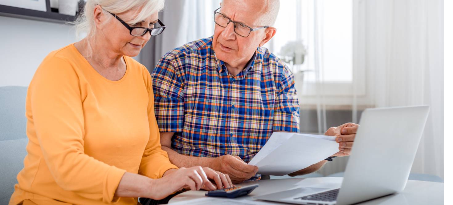 Worried senior couple checking bills using laptop at home