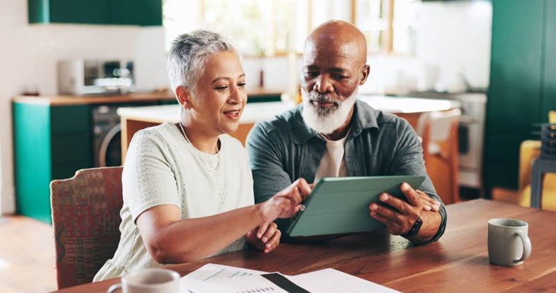 Senior couple, tablet and online for financial planning, paperwork and asset management at table.