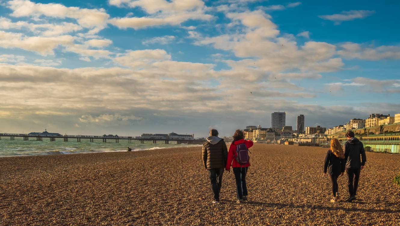 View of mature couple and  their teenage children walking on the beach in English seaside town 
