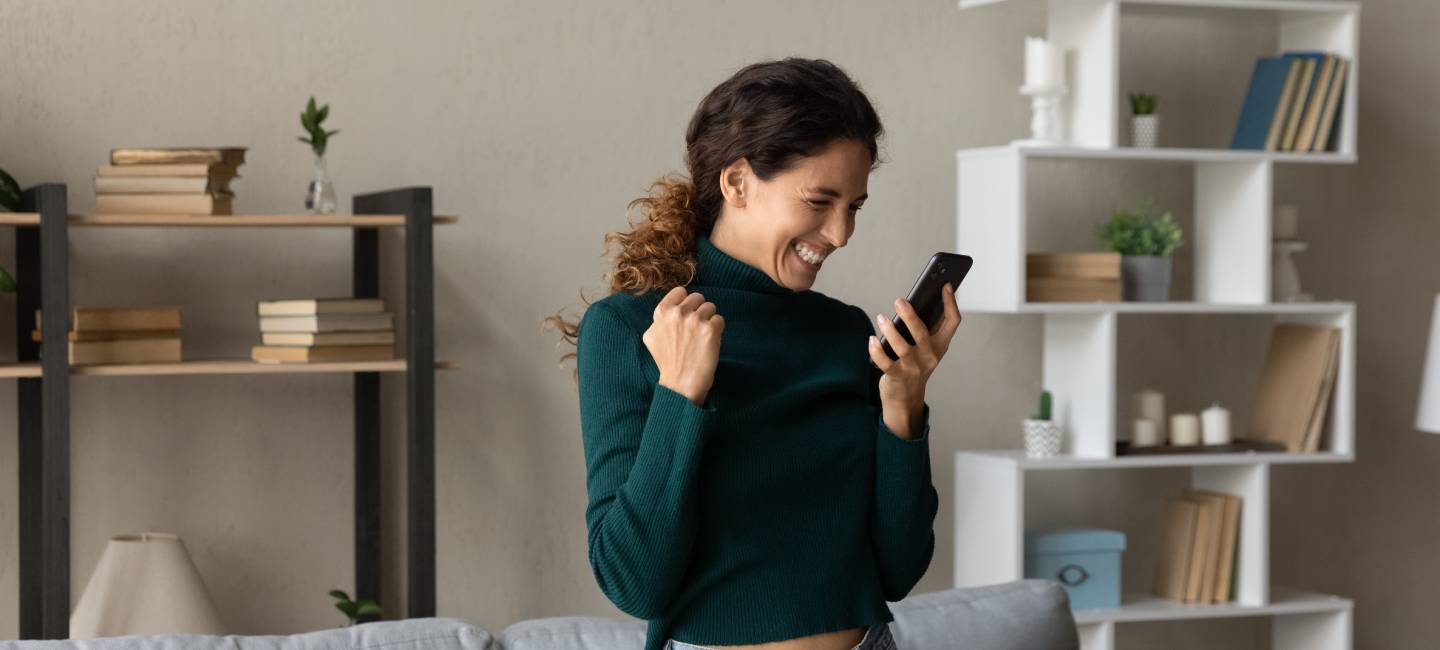 Overjoyed young woman looking at news of a win on her smartphone.