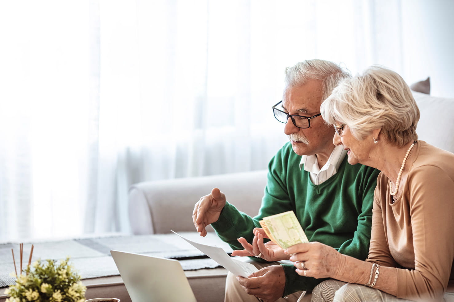 A mature couple having a conversation over paperwork while sat in front of a computer
