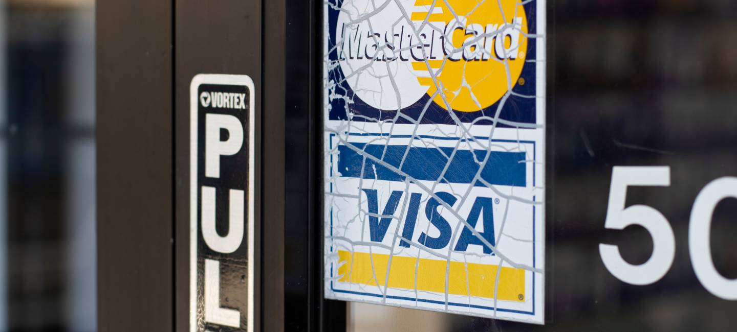 Weathered Mastercard and VISA payment acceptance sticker is seen at the entrance to a local business 