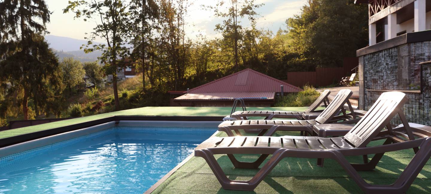 A background of two deck chairs and a swimming pool on AstroTurf, on a bright sunny day 