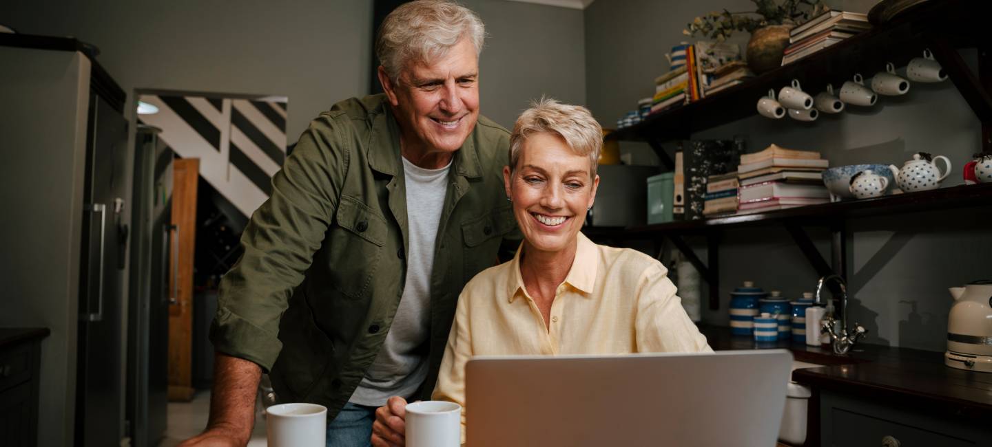 Mature couple looking at a laptop smiling 