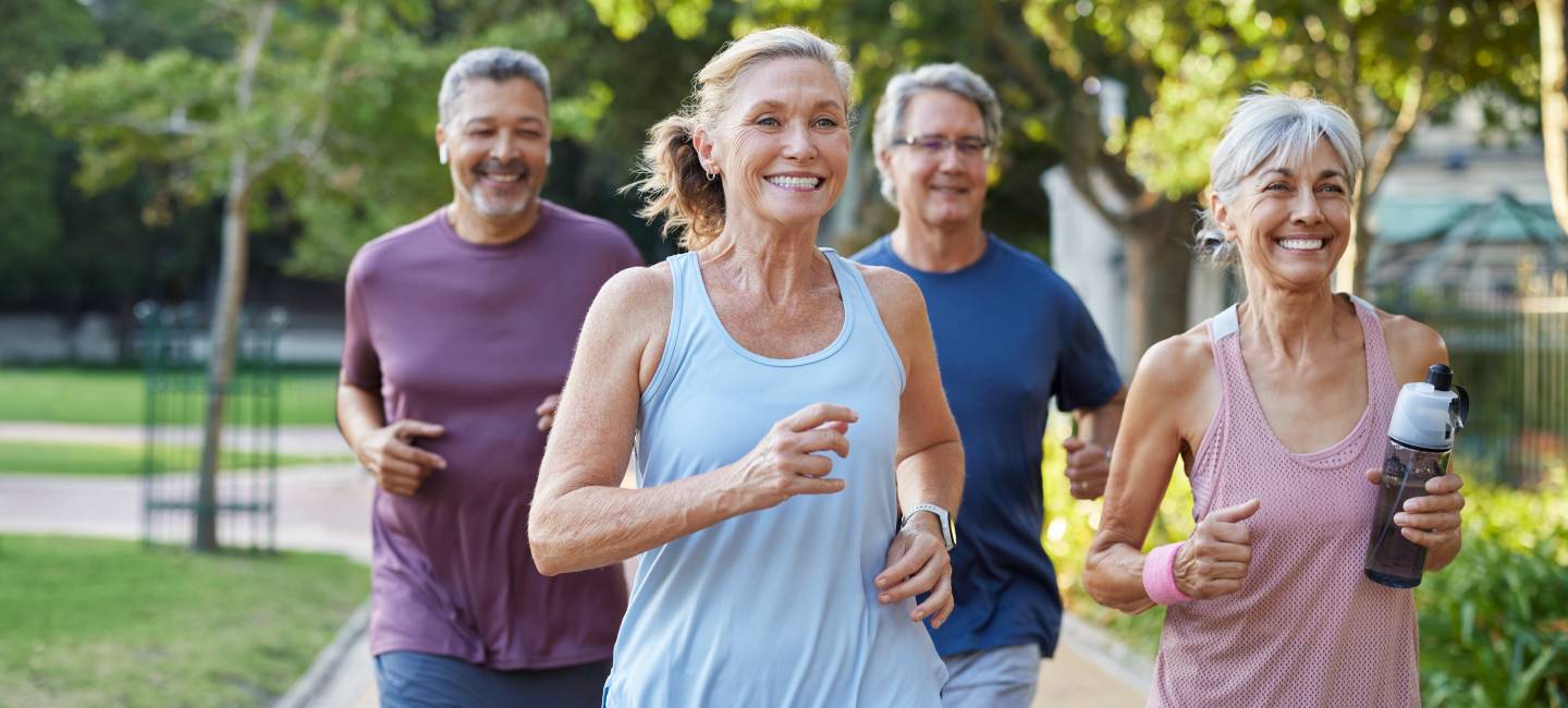 Group of happy older friends jogging in a city park