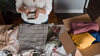 Woman taking a picture of her unwanted clothing items to resale online.
