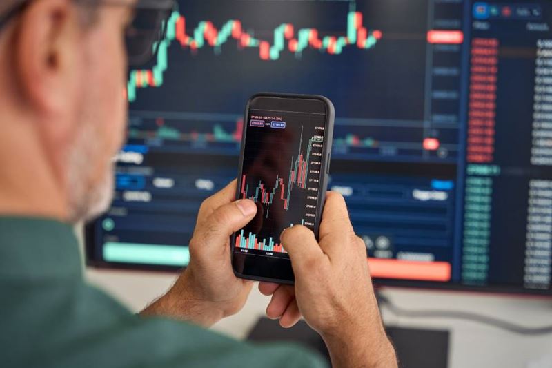 mature holding a mobile phone trading cryptocurrency on his phone