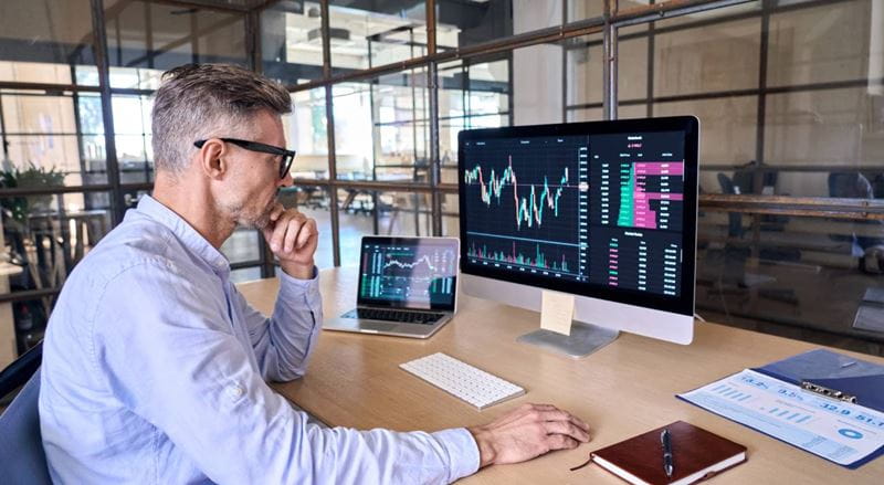 mature male sitting at a computer trading cryptocurrency