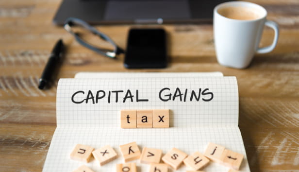 The words 'Capital Gains' on paper and the word 'tax' on scramble pieces