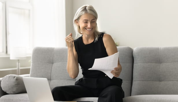 A woman sat on the sofa with paperwork in her hand. She is clearly happy!