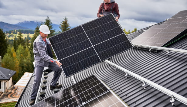A man is installing solar panels on a roof