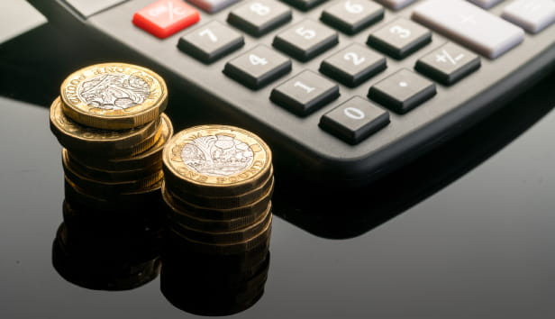 Pound coins stacked up next to a calculator