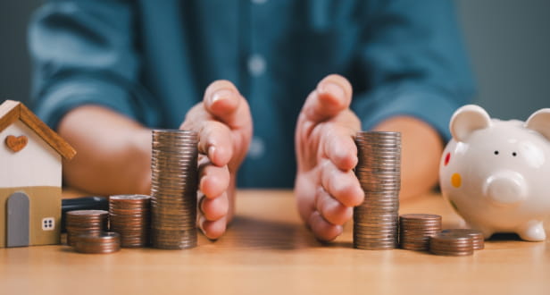 Divorce law and inheritance separation concept. Hand separate saving money, finance, home loan, debt return with piggybank and wood house. Bank business investment. Man separate stack coin on table.