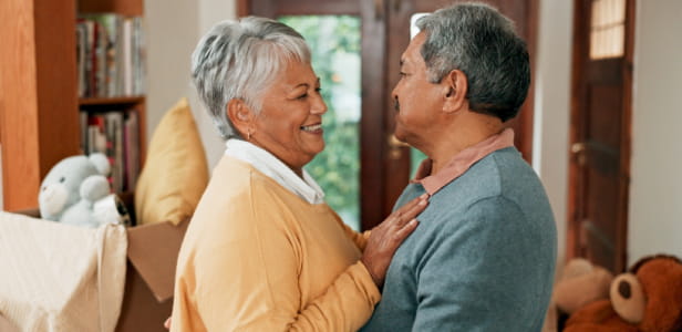 Love, moving and senior couple in home with hugging for happiness with new property for retirement. Smile, bonding and elderly man and woman embracing for new house with cardboard box together.
