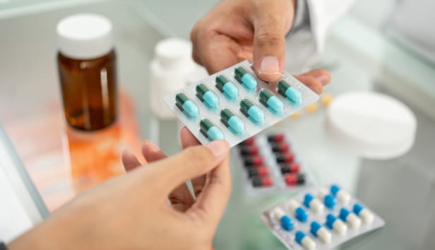 Pharmacist recommends medicines to customers. Asking the questions of medication. Professional Asian male pharmacist giving prescription medications to female patient customers at drugstore shelves.