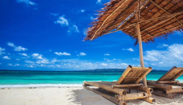 Beach chairs and umbrella on a beautiful tropical sea beach, view with copy space.