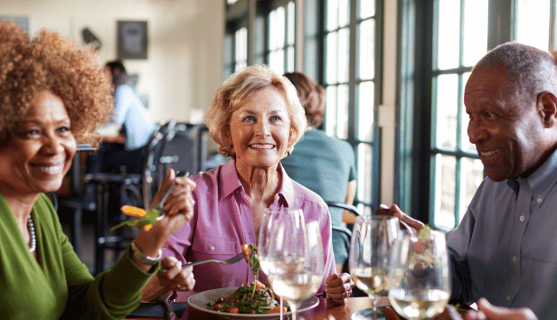 Group Of Smiling Senior Friends Meeting For Meal In Restaurant