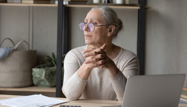 Stressed pensive middle aged woman in eyeglasses looking in distance, thinking of financial problems, suffering from lack of money, feeling stressed analyzing domestic expenditures or planning budget.
