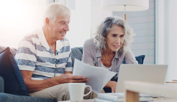 Paperwork, old couple and research for retirement, house and financial report of senior people and planning. Happy, laptop and investment of fund, online and documents for pension in lounge of home.