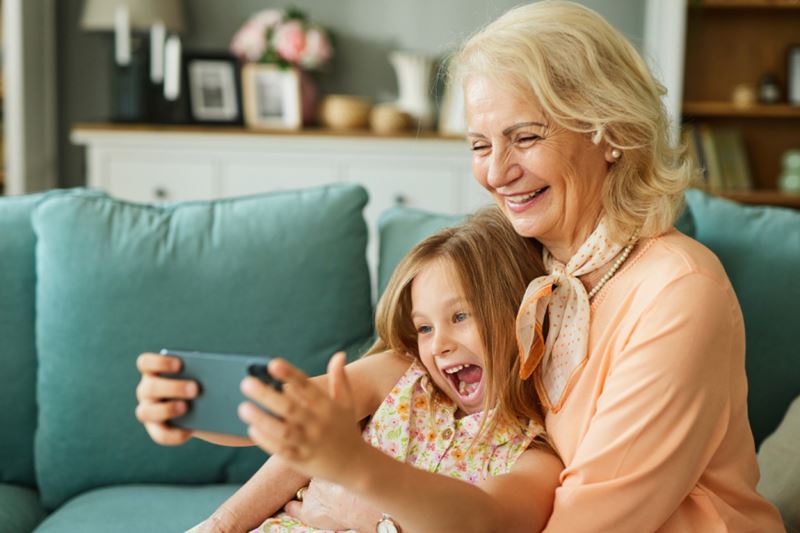 Woman and her granddaughter looking at her phone smiling