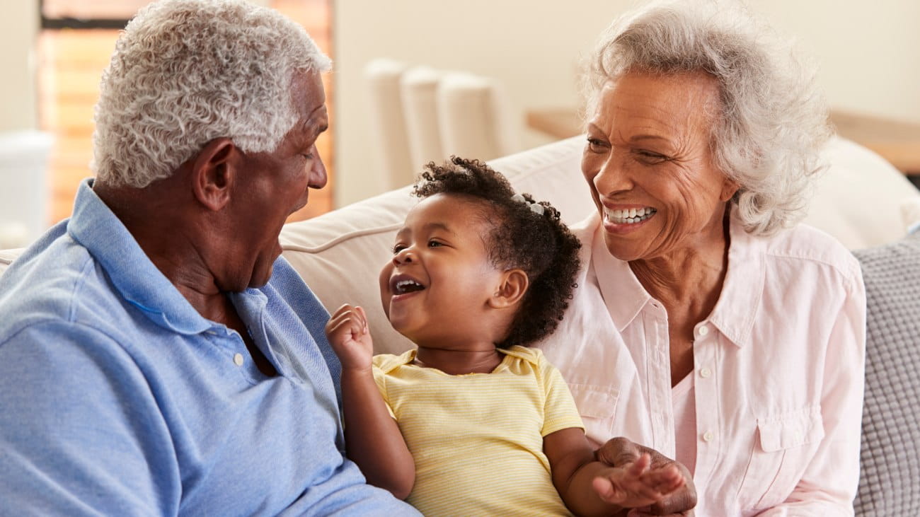 A little girl sitting between her two grandparents - all are very smiley