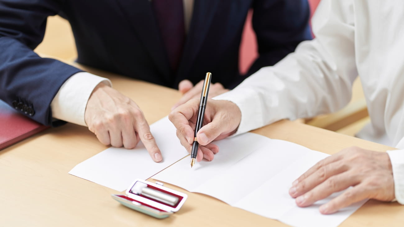 Two men sat at a desk signing official documents