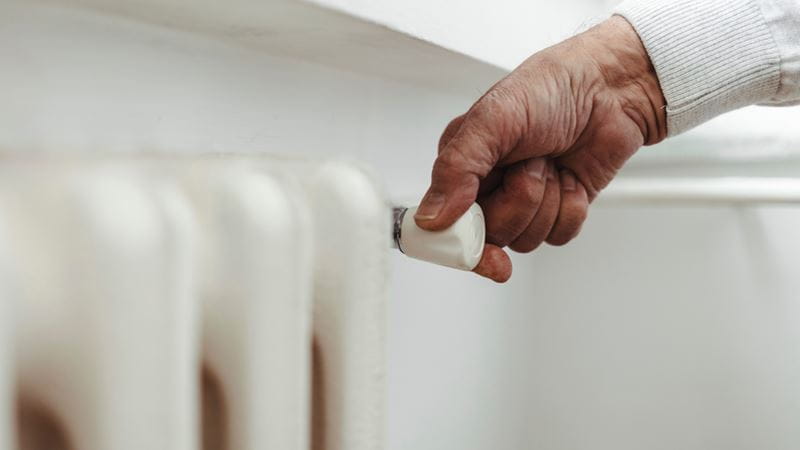 A person turning a radiator knob