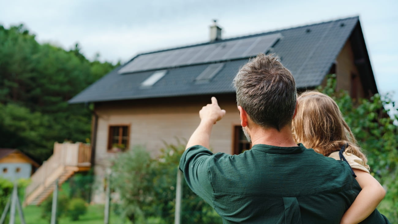 A man holding his child pointing at a house