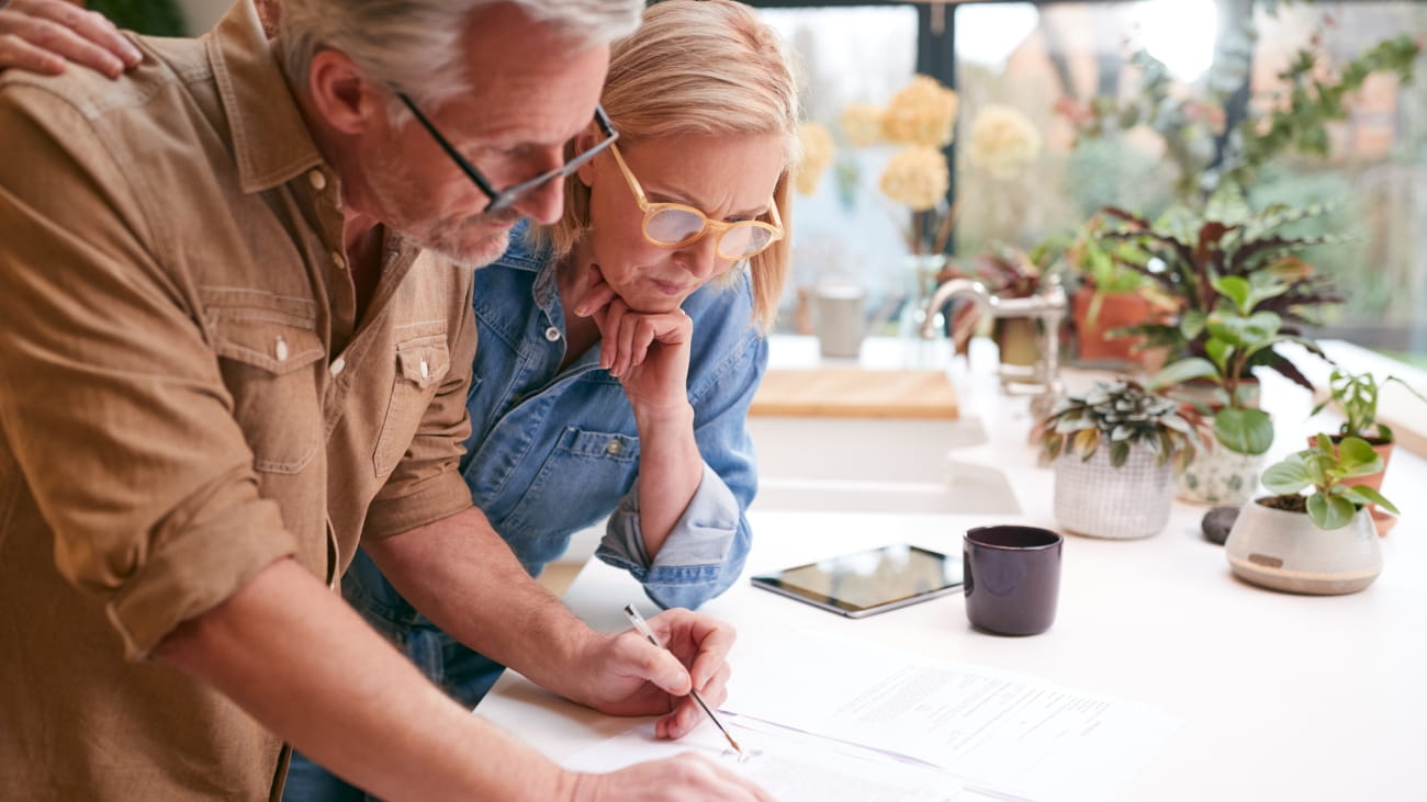 A couple leaning over their kitchen table, reviewing some paperwork