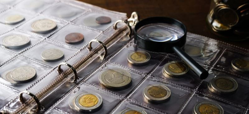 A book of old coins and a magnifying glass