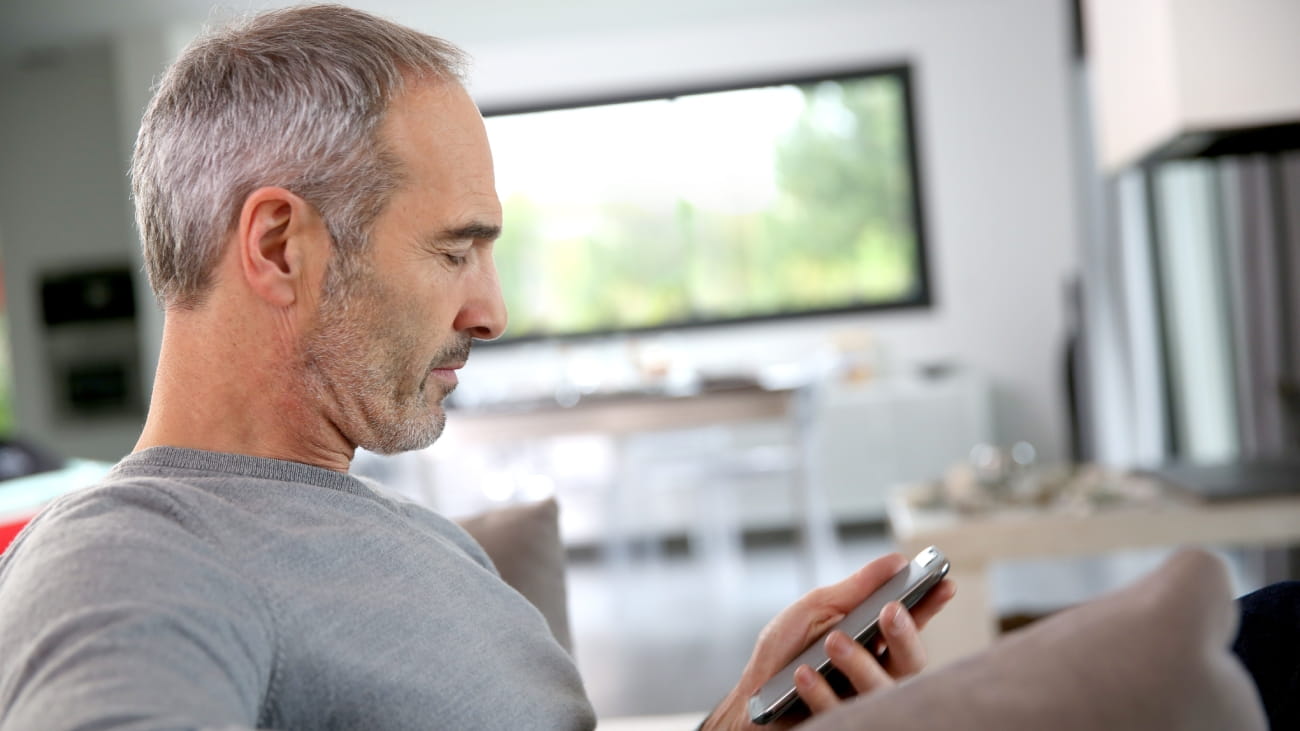 A man sat looking at his smartphone