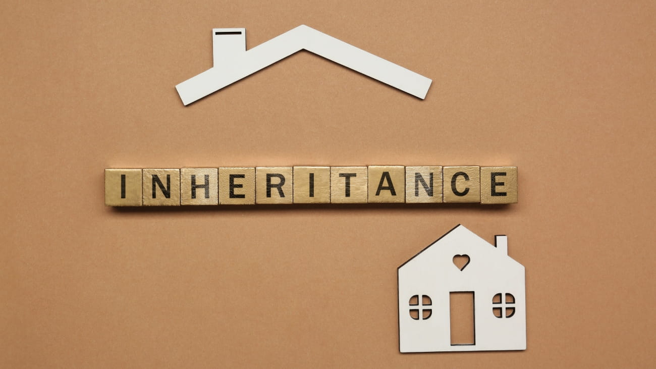 Word Inheritance made with wooden cubes and house model on brown background, flat lay