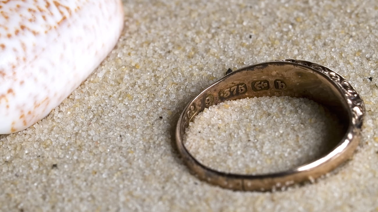 A 9ct gold ring on the beach with hallmark clearly displayed.