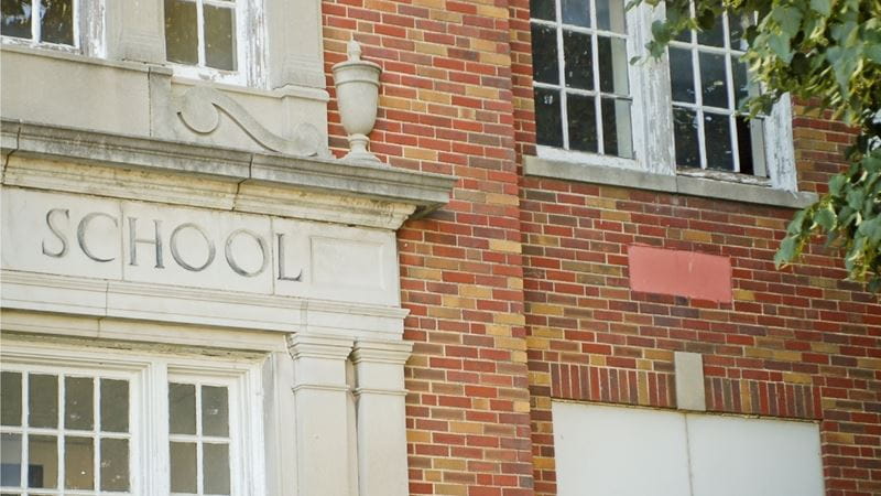 A school sign in carved into stone, on red brick building.