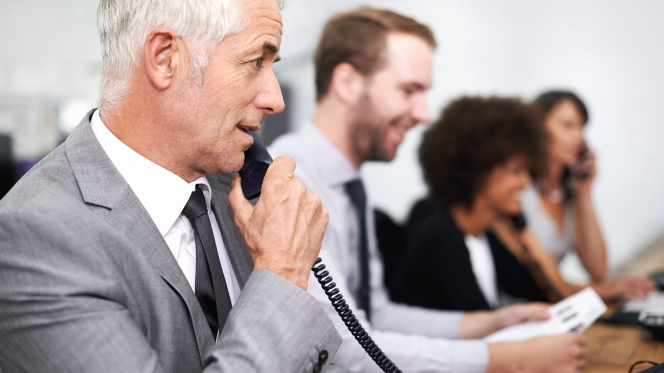 Call center, man and landline in office for customer service with telemarketing, help desk and conversation. Senior, employee and face of consultant with telephone for support, telesales and advice