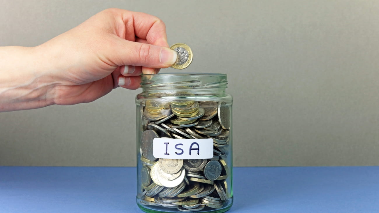 A hand putting money in a jar, labelled ISA