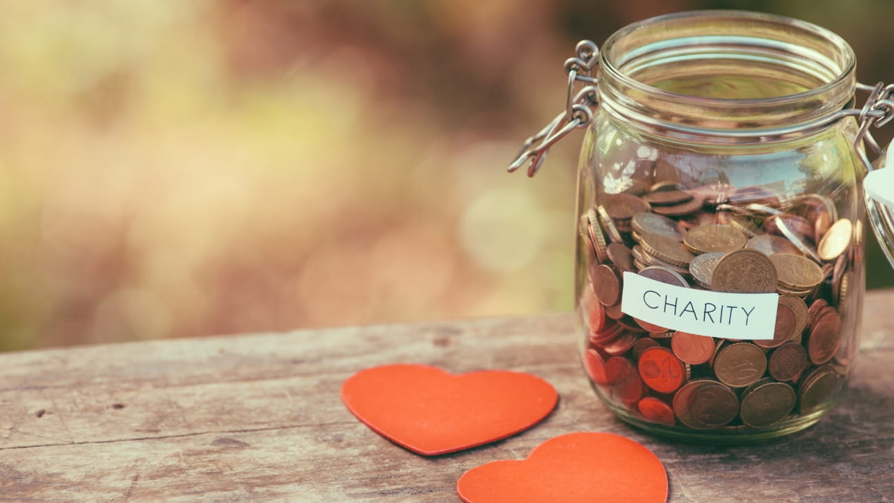 Money jar full of coins for charity and a couple of heart shapes