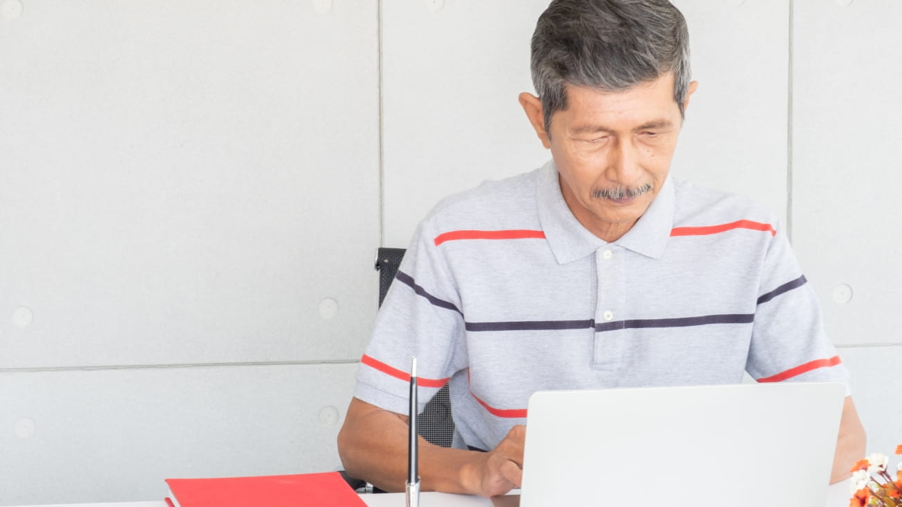 Senior Asian man using laptop computer in modern home office, businessman  planning via internet concept.