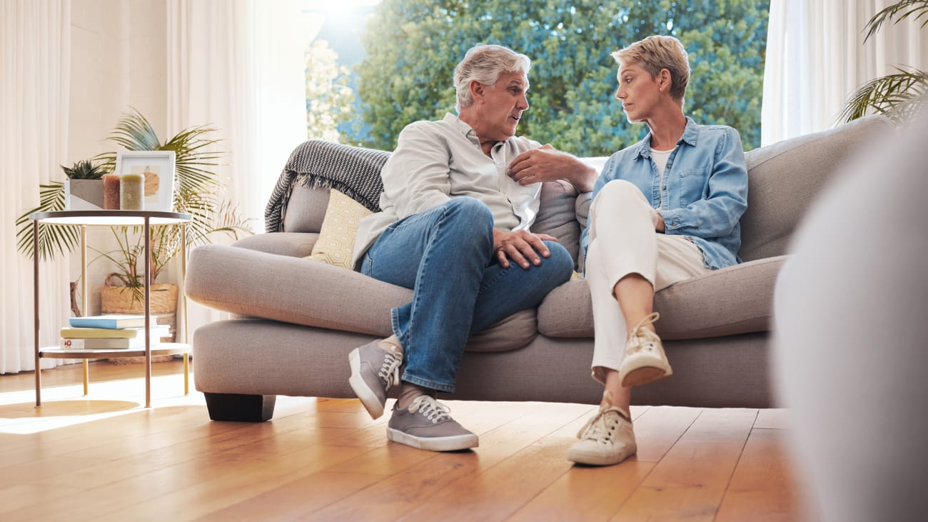 Senior couple, serious talk and communication about problems and marriage issues while sitting on the sofa at home. Mature man and woman talking and discussing issues, trouble and divorce.