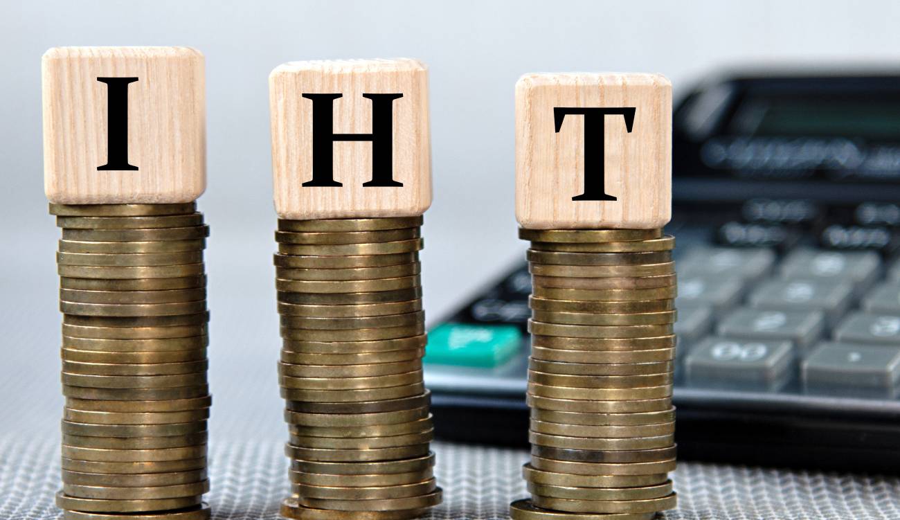 IHT (Inheritance Tax) - acronym on wooden cubes on the background of coins and calculator. Business and finance concept