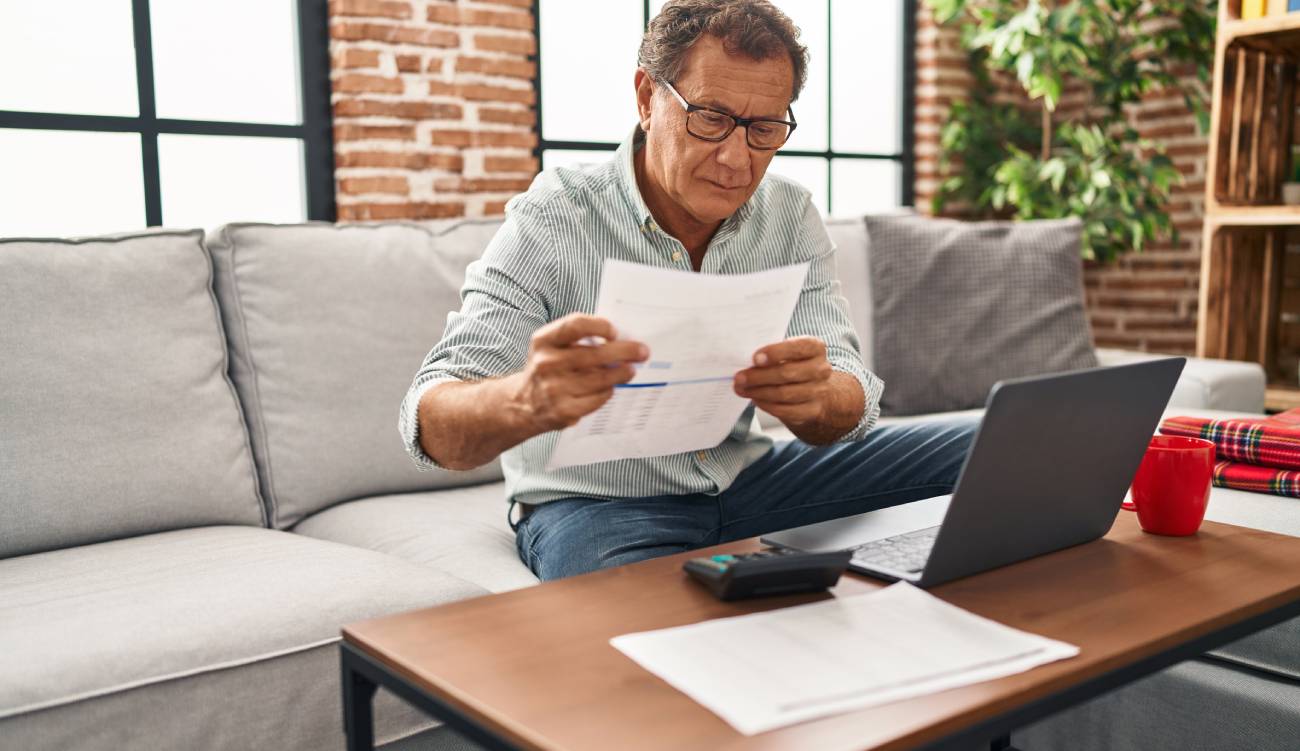 a mature man looking at a pension statement while calculating 