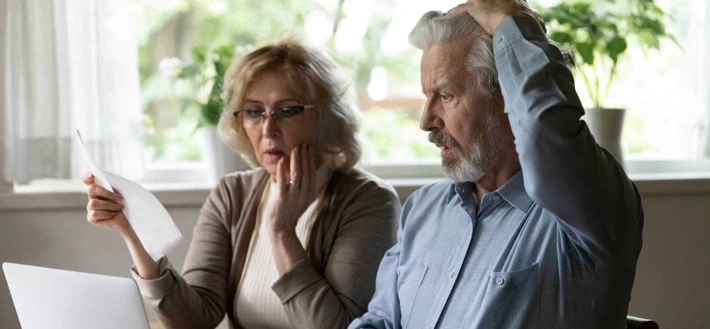 Unhappy shocked mature man and woman reading documents, pension tax letter