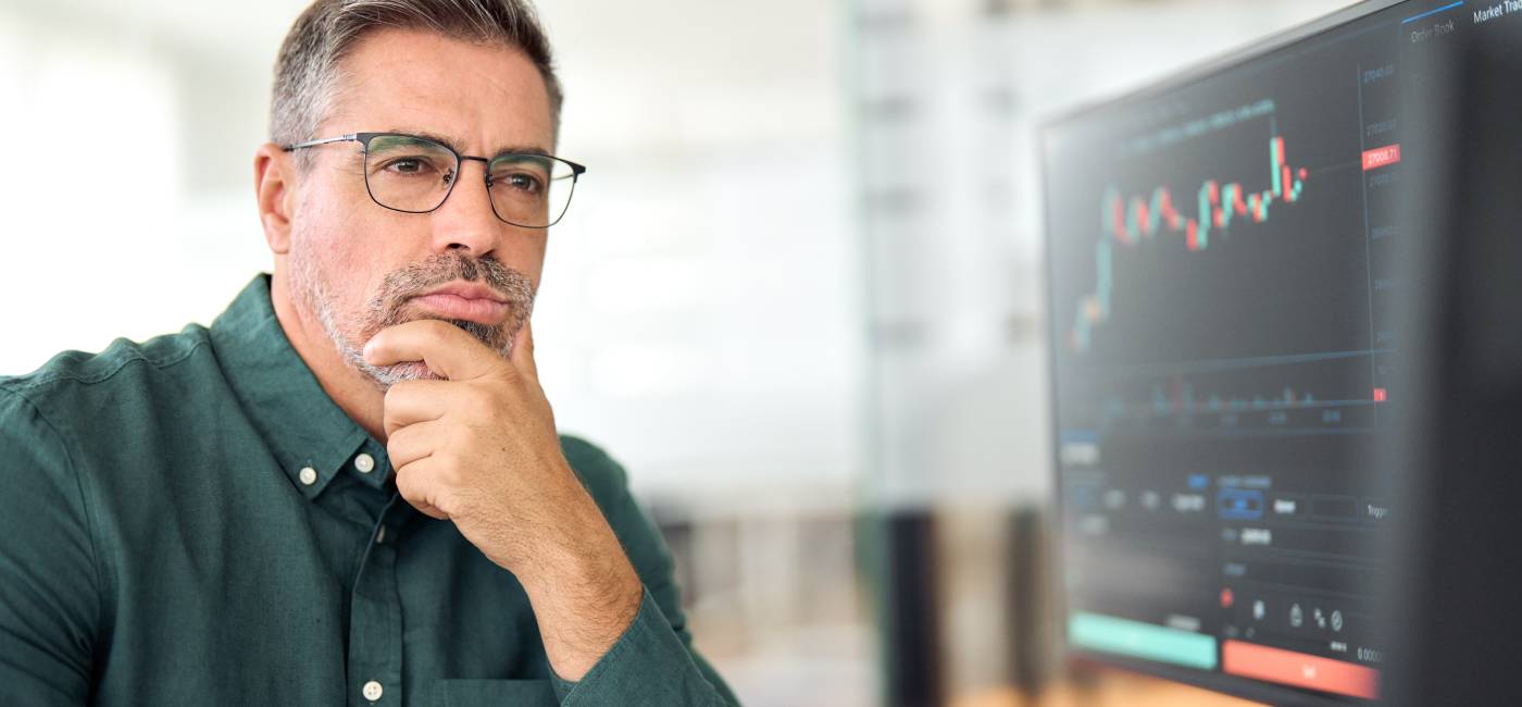 middle aged busy stock trader expert analysing online stock market data thinking of investing in digital trading exchange