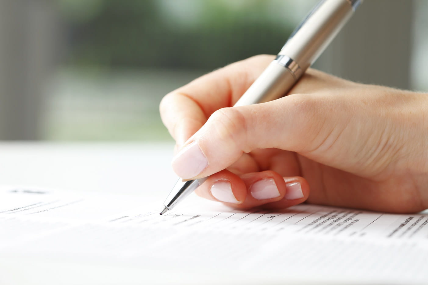 A hand holding a pen over some paperwork