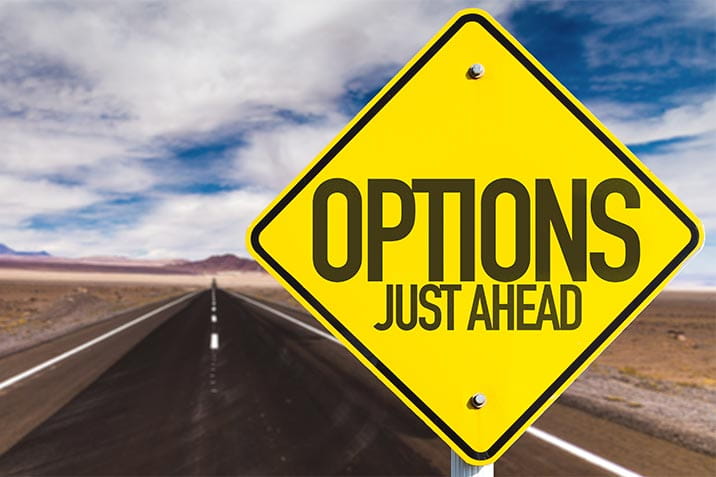 Yellow sign which reads 'options just ahead' with a road in the background