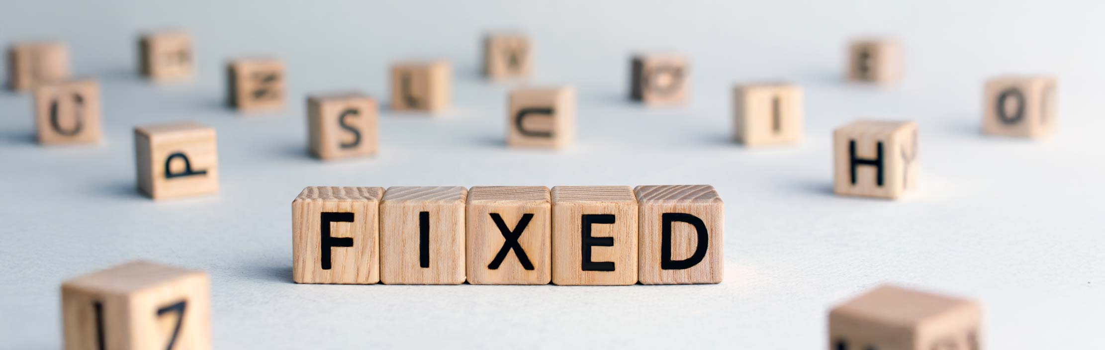 Fixed - word from wooden blocks with letters, fixed interest rates or costs  concept, random letters around, top view on wooden background